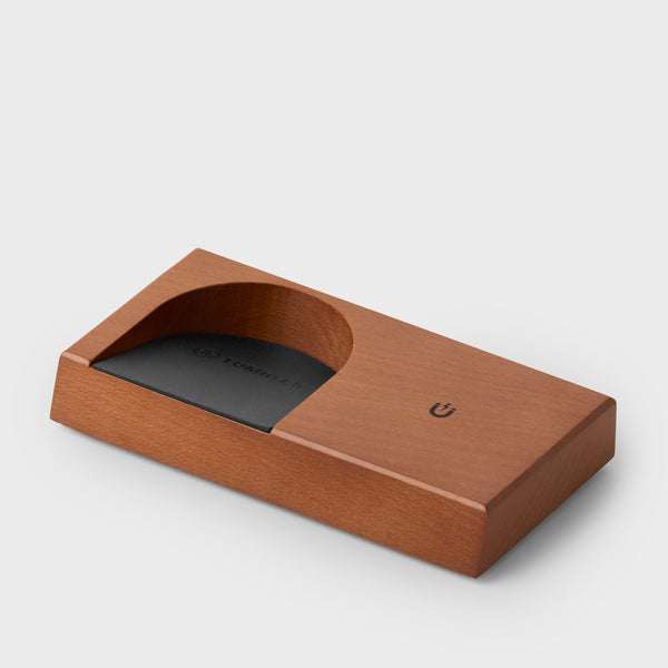 Corner view of a wooden tumbler protective stand with a black recessed slot.