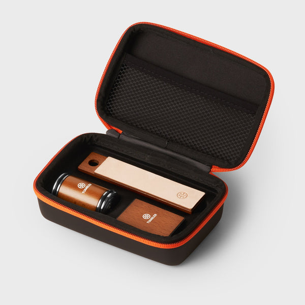Open orange zip case showing Tumbler Mini Sharpening Set with wooden sharpening pieces inside a black padded interior
